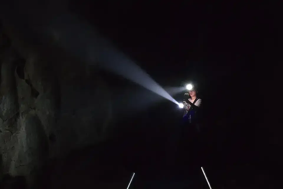 Besucher mit Lichtstrahl im dunklen Höhleninneren